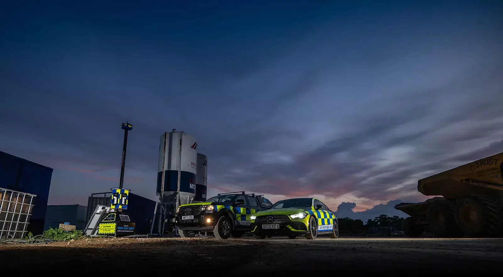 Sitewatch CCTV tower and deployment vehicles on a construction site at dusk